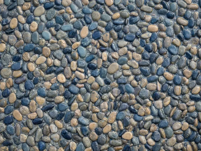 Close-up of a pebble aggregate pool finish with small rounded stones set in cement