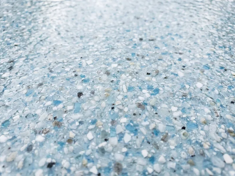 Close-up of a quartz aggregate pool finish speckled with white and blue granules